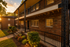 Charming apartment building showcasing inviting exterior with intricate iron railings, warm brick facade, and vibrant landscaping, enhanced by a golden sunset glow.