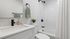 Modern bathroom with sleek white vanity, stylish black fixtures, and elegant shower area.