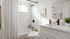 Modern bathroom with sleek design, featuring a white bathtub, stylish black fixtures, and a refreshing potted plant on the vanity.