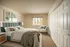 Inviting bedroom with a stylish green headboard, cozy chair by the window, and ample closet space.