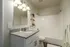 Modern bathroom with granite countertop, ample lighting, and sleek shelving.