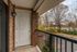 Inviting balcony with brick accents and scenic view of lush trees and suburban landscape.