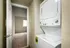 Efficient laundry area with a stacked washer and dryer set adjacent to cozy bedroom with carpet flooring.