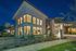 Elegant apartment exterior at night showcasing expansive windows and modern architectural design with lush landscaping.