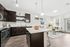 Modern open-concept kitchen and living room with sleek dark cabinets, a stylish granite island, and cozy seating area illuminated by natural light.
