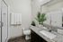Modern bathroom with granite countertops, glass shower, and lush plants for a refreshing ambiance.
