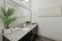 Modern bathroom with granite countertop, elegant fixtures, and stylish decor including a lush plant and geometric wall art.