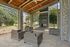 Chic outdoor seating area with modern wicker furniture, cozy fireplace, and inviting natural surroundings.