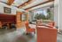 Chic lounge with modern orange seating, wood accents, and large windows offering a serene garden view.