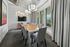 Elegant meeting room with modern chandeliers, sleek wooden table, and plush gray chairs, framed by large windows for ample natural light.
