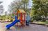 Charming outdoor playground with vibrant slides and climbing structures surrounded by lush greenery and pathways.