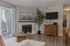 Living room featuring a cozy fireplace, sleek wooden furniture, and natural light streaming through sliding glass doors.