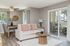 Bright and inviting living and dining featuring a cozy beige sofa, wooden coffee table, and elegant dining table with natural light.