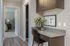 Chic home office nook with sleek desk, modern chair, and vibrant plant, leading to a cozy bedroom with soft lighting.