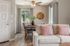 Inviting living area with plush cream sofa, accented by soft pink pillows, leading to a cozy dining nook with a wooden table and modern decor. Bright, airy space perfect for relaxation and entertaining.