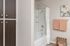 Chic bathroom with wooden cabinetry, modern bath area, and soft pastel decor for a relaxing ambiance.