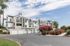 Elegant apartment community with modern architecture, lush landscaping, and spacious garages under a clear blue sky.