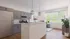 Elegant modern kitchen with sleek cabinetry, stainless steel appliances, and stylish pendant lighting. Sunlit dining area with large windows and lush greenery.
