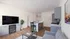 Modern open-concept living area featuring a sleek kitchen island, stylish gray cabinetry, elegant hardwood flooring, and vibrant wall art. Perfect for contemporary living.