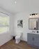 Modern bathroom with sleek lighting, elegant wood flooring, and stylish gray vanity, creating a serene and inviting atmosphere.
