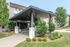 Inviting apartment entrance with modern canopy, lush landscaping, and well-maintained surroundings.