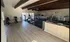 Spacious gym with modern fitness equipment including treadmills, ellipticals, and stationary bikes, featuring stylish wood beam ceiling and natural light.