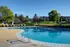 Inviting outdoor pool with lounge chairs, surrounded by lush greenery and residential buildings, on a sunny day.