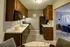 Modern kitchen with sleek dark wood cabinets, stainless steel sink, and cozy dining area opening into a stylish living room.