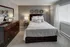 Elegant bedroom featuring a cozy bed with plush pillows, tasteful wall decor, and ample natural light from large windows.