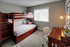 Cozy bedroom featuring elegant wooden bunk beds with soft gray bedding, a sunlit workspace with a sleek desk and chair, perfect for productivity.