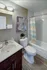 Charming bathroom with elegant wood cabinetry, vibrant artwork, and a modern shower curtain, creating a cozy atmosphere.