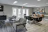Modern communal lounge with elegant seating, computer stations, and natural light through glass doors.