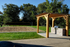 Beautiful outdoor area with a sand volleyball court and a stylish pergola with a built-in grill, surrounded by lush greenery.