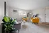 Bright and cozy living room with modern decor, featuring vibrant yellow armchairs, a soft gray sofa, and lush greenery for a welcoming atmosphere.