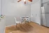 Chic dining nook with modern table and chairs set against a stylish white brick wall, complete with sleek wooden flooring and stainless steel refrigerator.