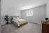 Inviting bedroom with plush carpet, elegant bedding in yellow and gray tones, and tasteful decor for a cozy atmosphere.