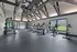Modern apartment gym with sleek cardio machines, weightlifting equipment, and bright natural lighting through large windows.