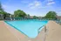 Inviting outdoor pool area with crystal-clear water, surrounded by lounge chairs and lush greenery, perfect for relaxation and leisure.