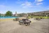 Spacious outdoor patio with picnic tables beside a refreshing pool, surrounded by modern apartments under a clear blue sky.