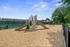 Inviting playground with slides and climbing wall, surrounded by lush greenery and a sunny sky.