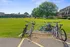 Charming apartment complex with lush green spaces, bicycle racks, and a nearby playground under clear blue skies.