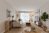 Inviting living room with modern decor, large windows, and cozy seating area featuring stylish furniture and lush greenery.