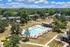 Aerial view of a serene apartment complex with a sparkling outdoor pool surrounded by lush greenery and modern buildings.