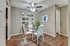 Elegant dining area with a modern glass table, sleek white chairs, and contemporary decor, featuring a stylish ceiling fan and wood flooring.