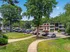 Charming apartment complex nestled in lush greenery, featuring ample parking and inviting outdoor spaces.