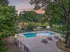 Serene pool area at sunset, surrounded by lush greenery and elegant seating, featuring a scenic pond with fountain.