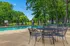 Inviting outdoor swimming pool area with stylish lounge chairs and patio tables, surrounded by lush green trees offering a serene retreat.