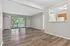 Bright and spacious living room with elegant wood flooring, large windows, and a charming open kitchen view.