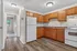 Inviting kitchen with warm wooden cabinetry, modern appliances, and sleek countertops leading to a bright hallway.