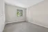 Bright and inviting bedroom space with plush carpeting, neutral walls, and a large window offering serene outdoor views.